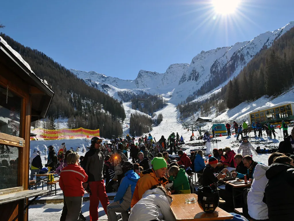 Volle Terrasse einer Skihütte im Gegenlicht der Sonne.